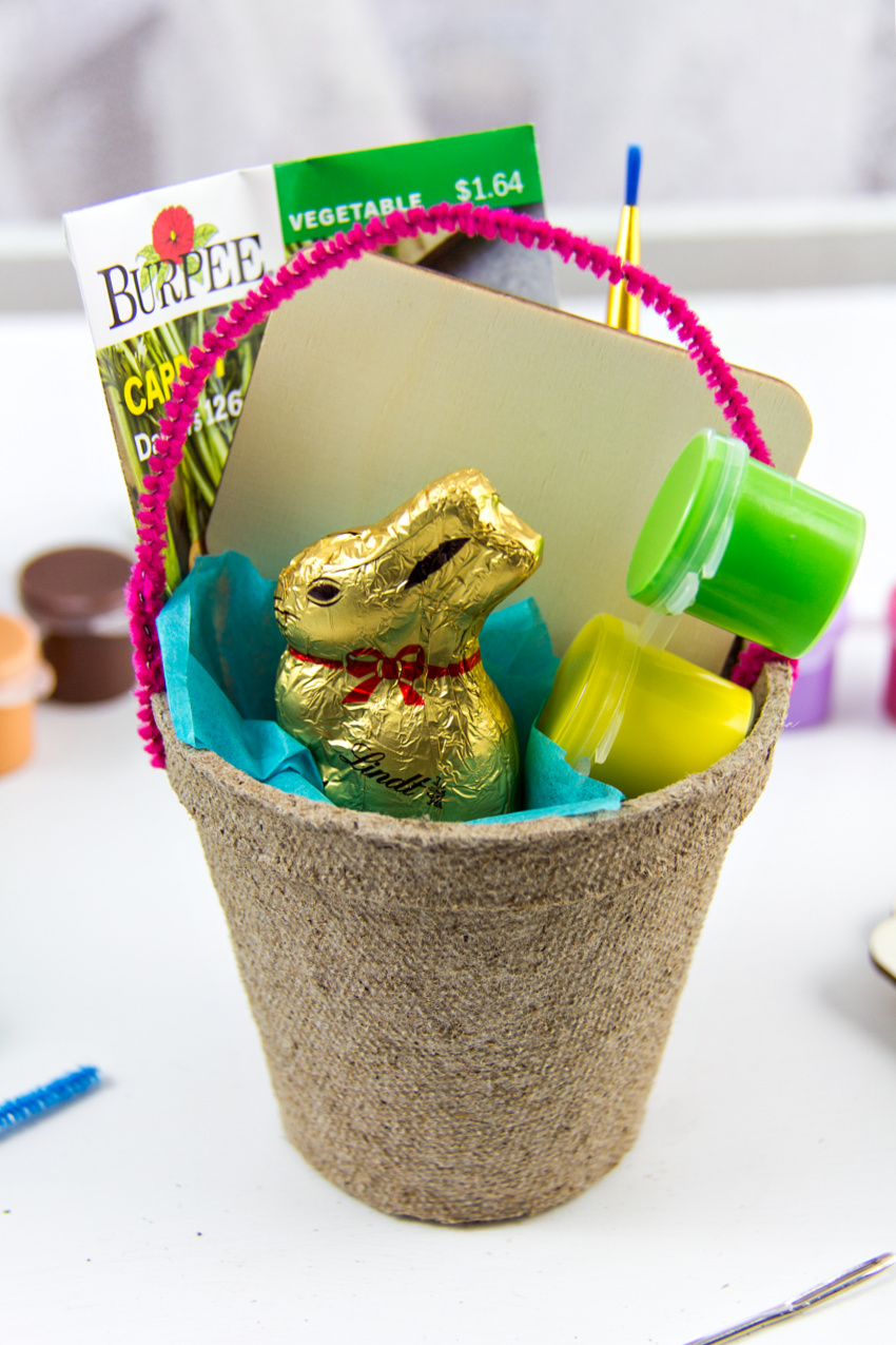 seed start pot turned into an easter basket and filled with seeds and a plant marker craft for kids