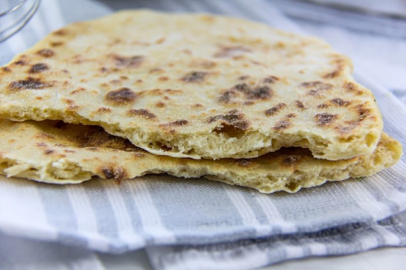 flatbread torn in half on a grey and white dishtowel
