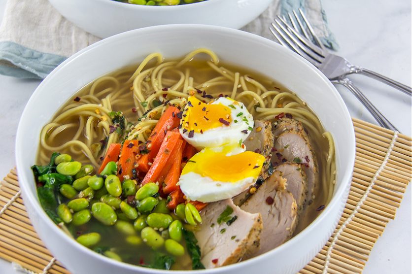 pork edamame and carrot with ramen noodles and egg in a bowl