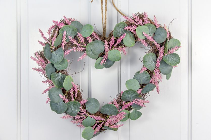 eucalyptus leaves and pink flowers on a natural heart shaped wreath