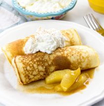 pancakes rolled and filled with cinnamon apple compote and then topped with freshly whipped cream, cinnamon, and salted caramel maple syrup