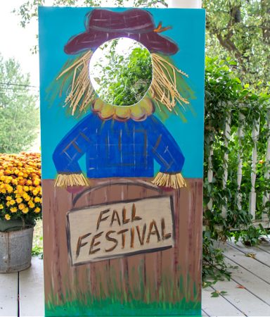 a diy plywood photo booth board for a fall festival with a picture of a scarecrow on it