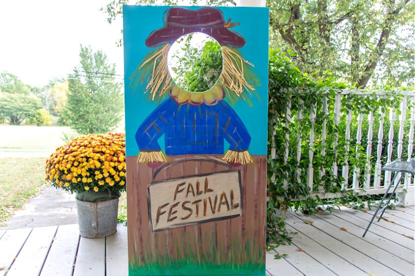 a diy plywood photo booth board for a fall festival with a picture of a scarecrow on it