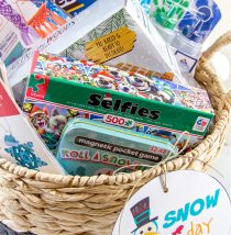 A basket full of activities for snow days including a jigsaw puzzles, games, and crafts