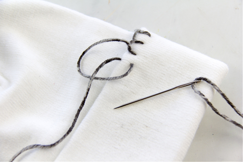 blanket stitch being used to embroider an edge on a beanie