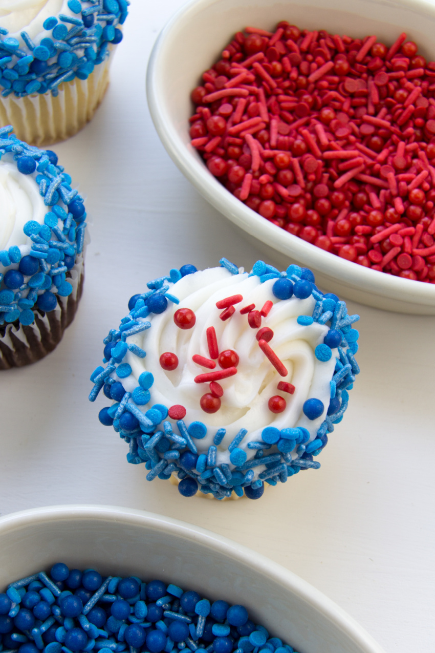 blue sprinkles around the edge of a cupcake and red sprinkles on top