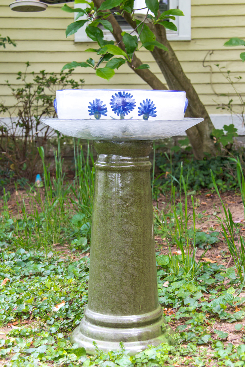 a diy bird bath made using a bird bath base, a glass tray, and a serving bowl