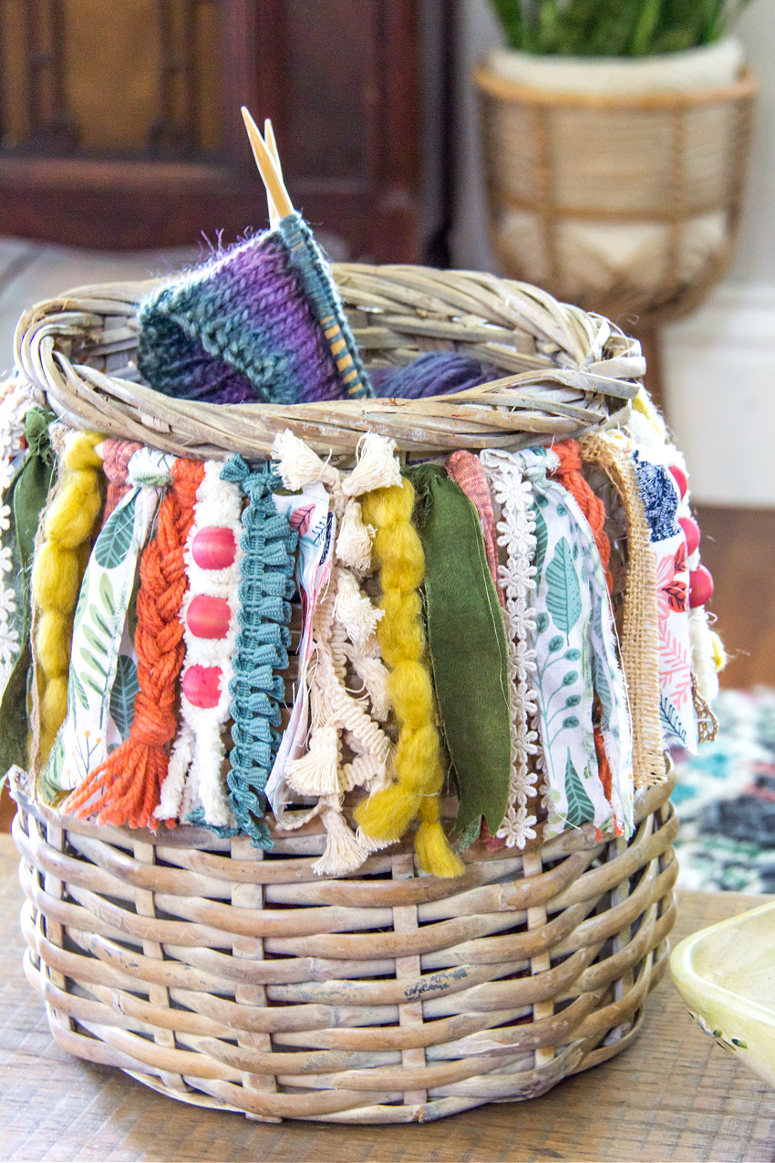 a basket with a boho fringe made out of yarn, ribbon, and beads.