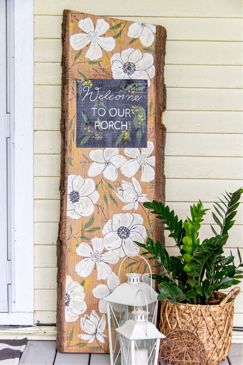 A hand painted diy welcome to our porch sign on white oak with flowers on it