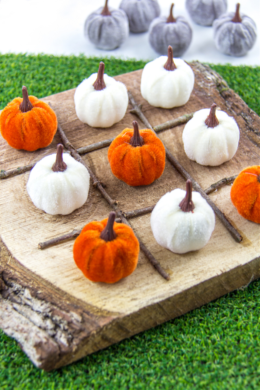 diy tic tac toe board using a wood slice, sticks, and tiny pumpkins