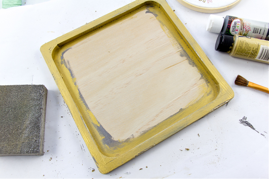 A wood frame painted with grey and gold and sanded to look worn