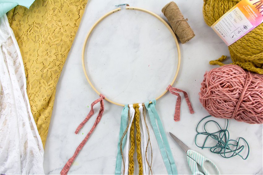 scraps of fabric, yarn, and hemp cord tied to an embroidery hoop to make a wall hanging