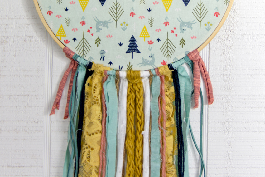 tassels on an embroidery hoop using yarn, fabric, lace, and cord