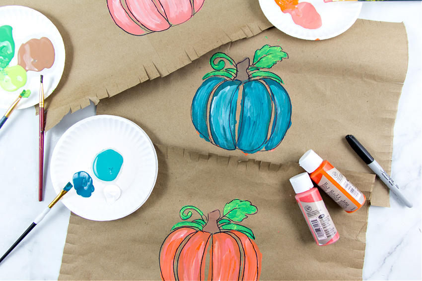 a pumpkin painted on brown paper and turned into a paper placemat for the kids Thanksgiving table