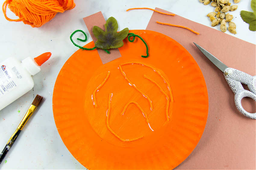 orange yarn added to a paper plate pumpkin for the fibrous strands