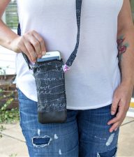 a lady wearing a white t-shirt and jeans with a black cross-body phone purse
