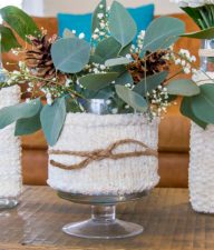 assorted vases wrapped in knit cozies and filled with winter flower arrangements