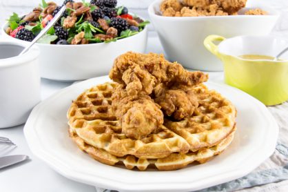 fried chicken and waffles on a plate with berry salad on the side