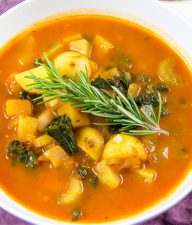 an autumn harvest soup in a bowl with a sprig of rosemary
