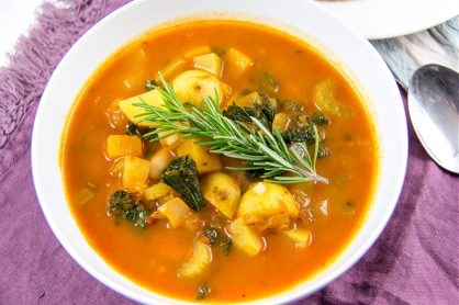 an autumn harvest soup in a bowl with a sprig of rosemary