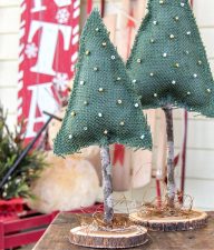 miniature christmas trees made out of green burlap, a stick, and a wood slice