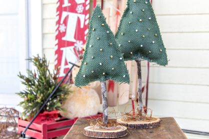 miniature christmas trees made out of green burlap, a stick, and a wood slice