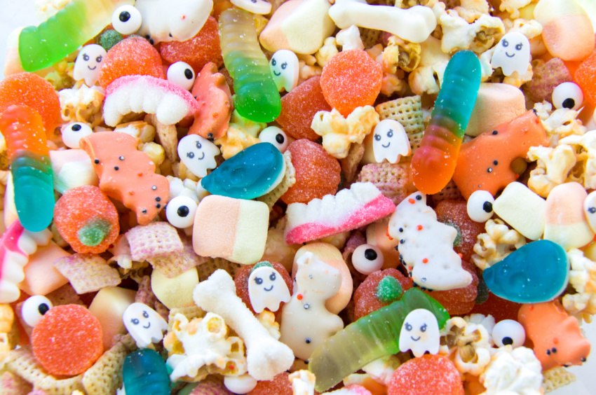 halloween snack mix with gummy teeth, worms, bones, pumpkins, and skulls, along with candy eyes and ghosts, popcorn, and Chex mix. 