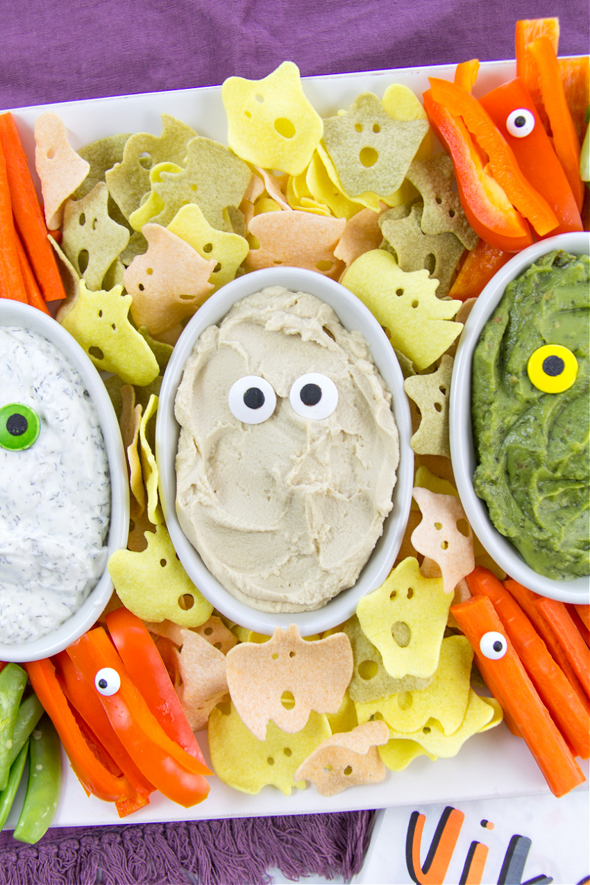 healthy halloween snacks including dips, ghost chips, and vegetable sticks