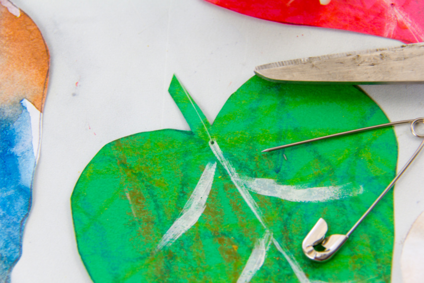 paper fall leaves being threaded together using fishing line to make a wall hanging