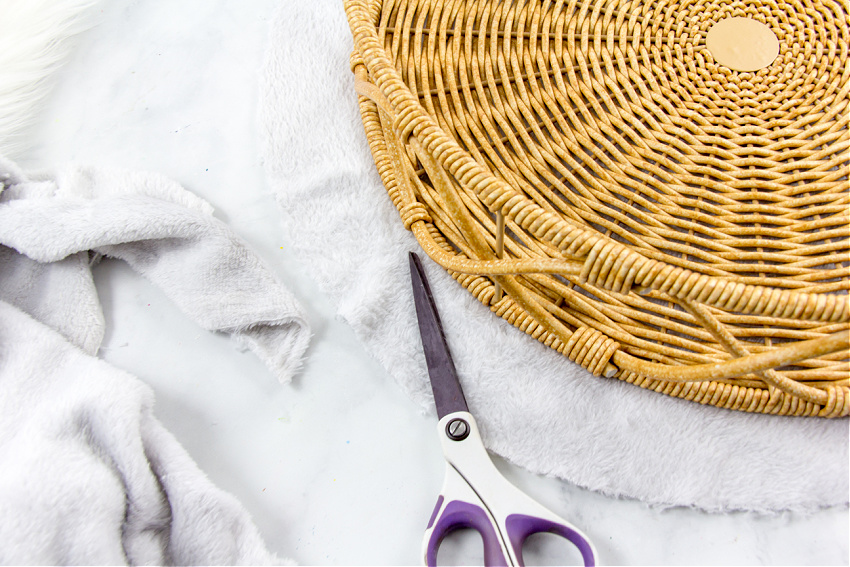 plush fabric being cut to make a dog bed in a basket