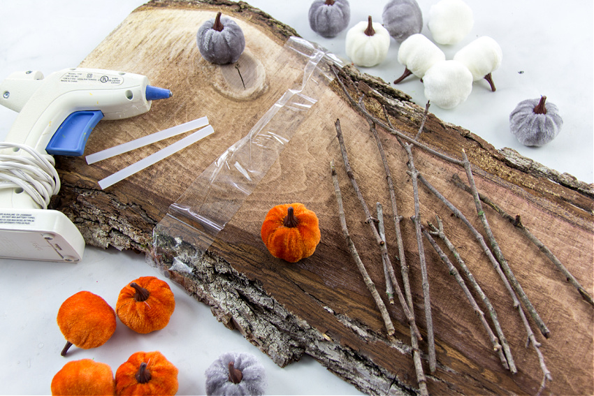 to make a diy tic tac toe board for fall you need a wood slice, twigs, glue, and mini faux pumpkins