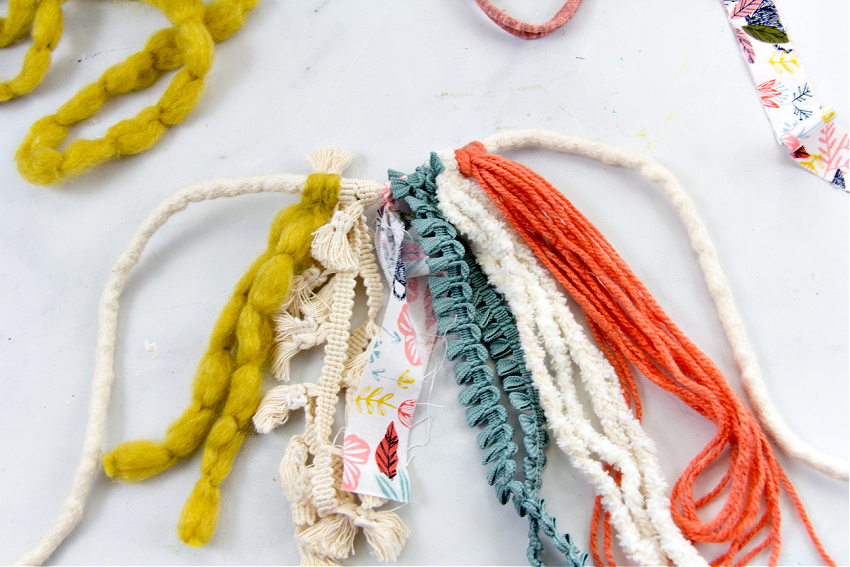 a decorative fringe for a basket made out of ribbon, yarn, and fabric