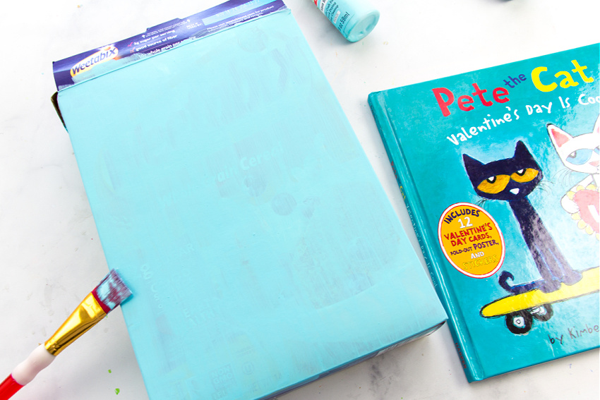 a cereal box being painted to make a valentines day box inspired by a pete the cat book
