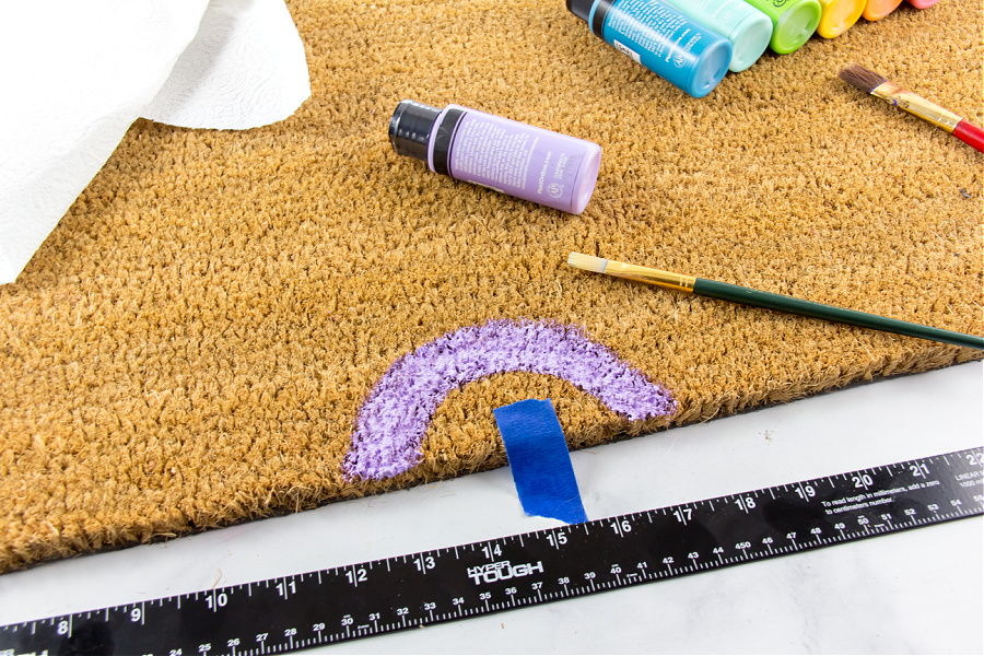 a purple arc painted on a coir doormat to begin a rainbow