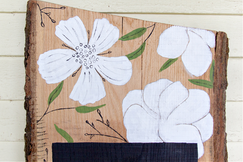 white flowers with black detail and green leaves painted on wood