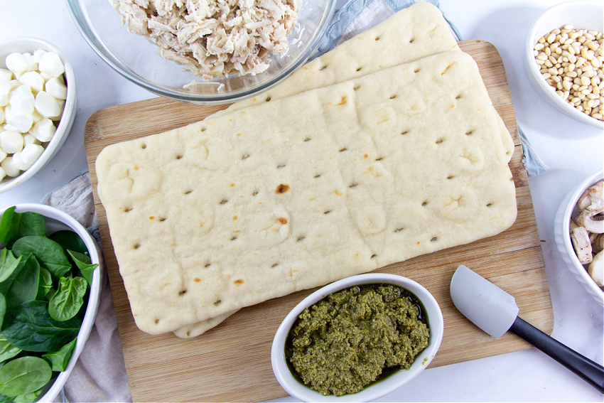 flatbread pizza bases, pesto, pine nuts, shredded chicken, spinach, and mozzarella