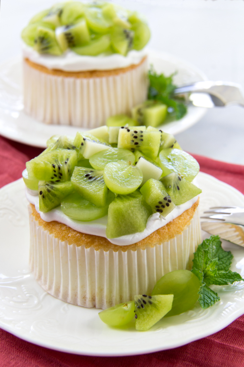 mini angel food cake topped with whipped cream, green grapes, and kiwi fruit
