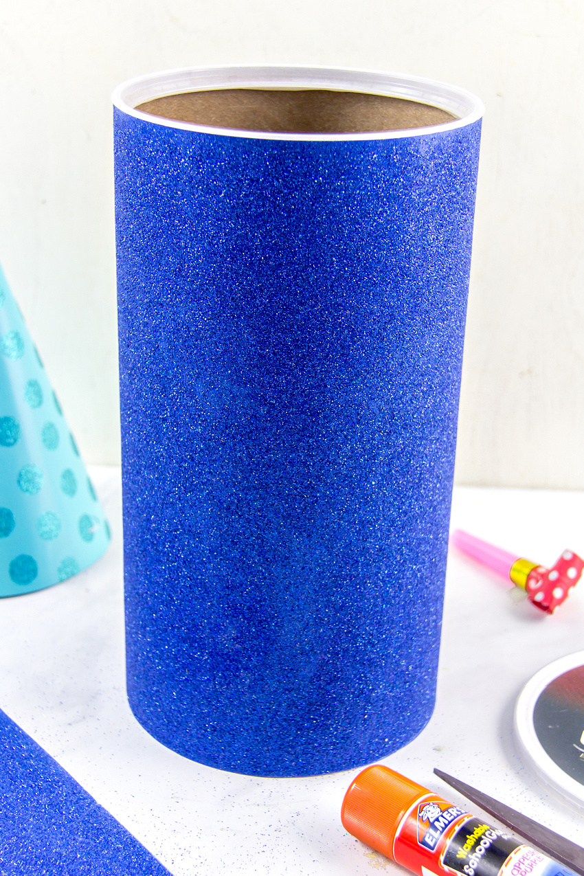 an oatmeal container wrapped in glitter scrapbook paper to make a gift container