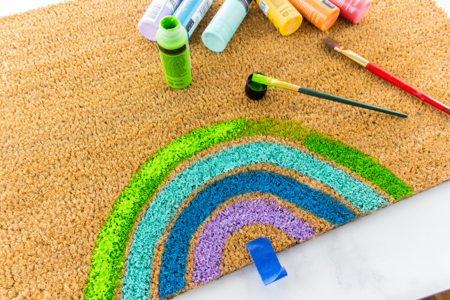 a rainbow being painted on a coir door mat