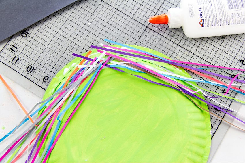 attach strips of colored paper to the paper plate to make hair for your witch