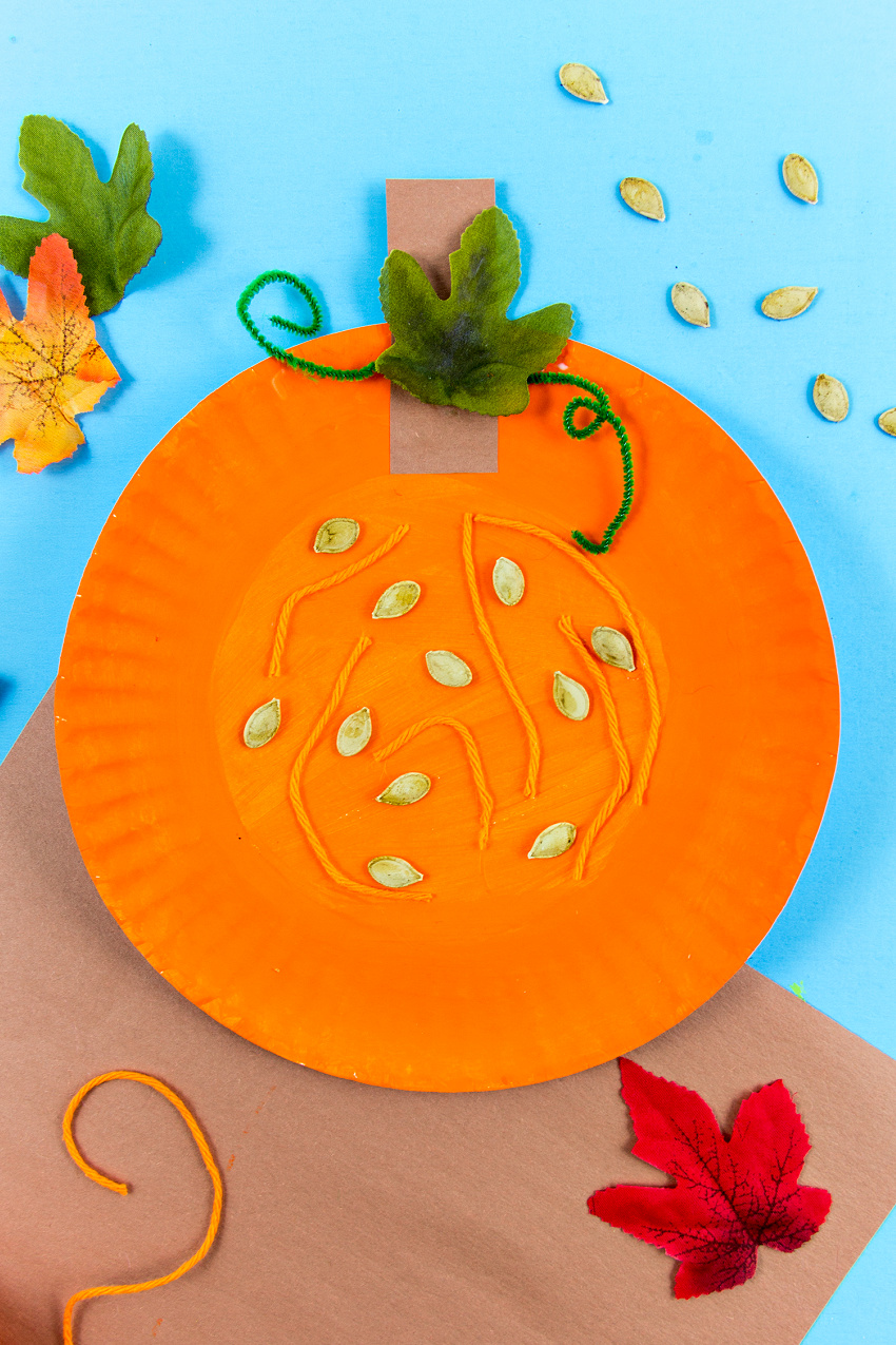 paper plate pumpkin that studies the parts of a pumpkin using seeds, string, pipecleaner, and paper
