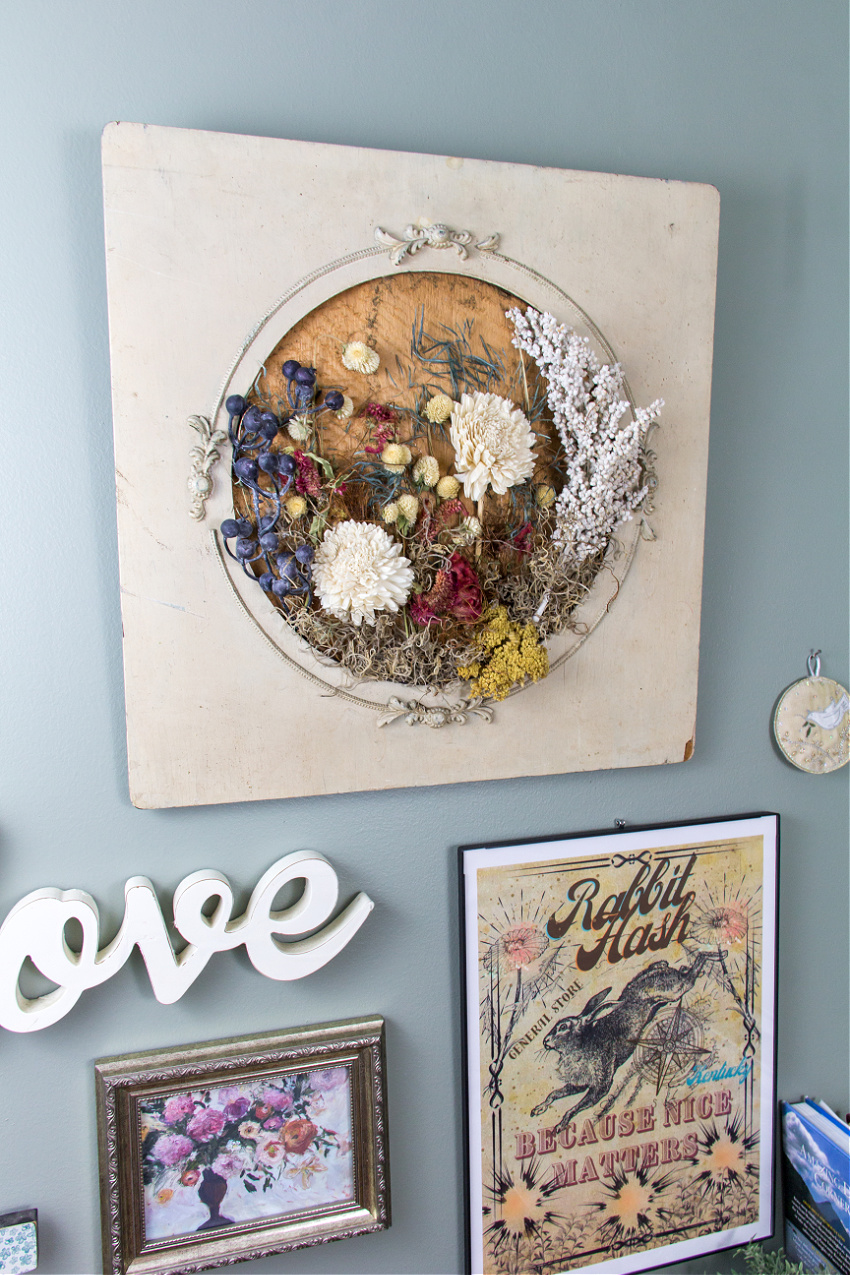 a wall gallery containing a word, painting, poster, and dried flower wall art