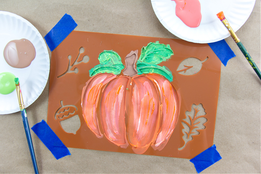 a pumpkin stencil on brown paper that's painted and turned into a placemat