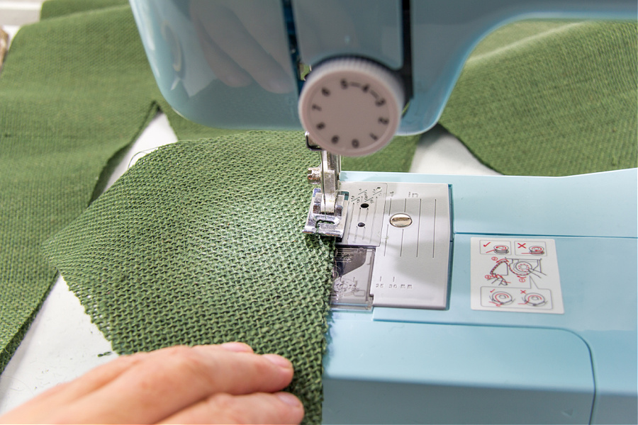 A green burlap christmas tree being sewn together using a sewing machine