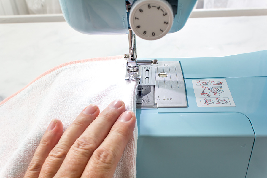 Sew the side seams of a tea towel together to turn it into a tote bag