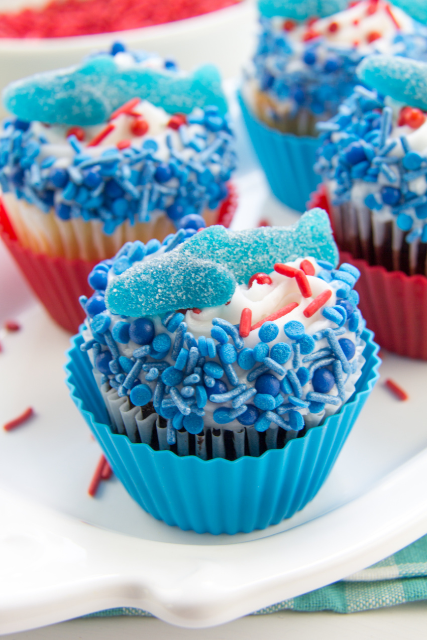 shark cupcakes made with chocolate cupcakes, buttercream frosting and topped with blue and red sprinkles and a gummy shark