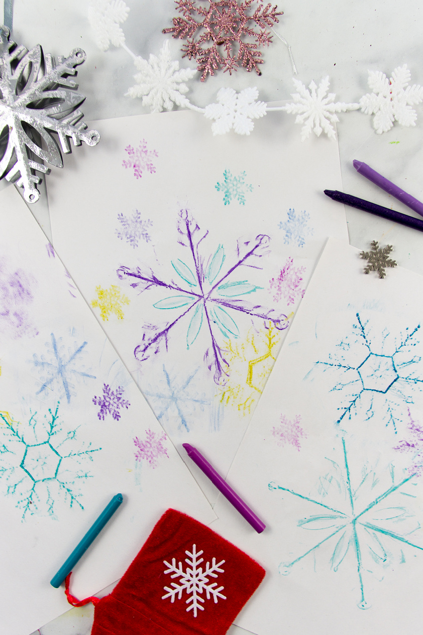 snowflake rubbing art made using crayons and Christmas snowflake ornaments