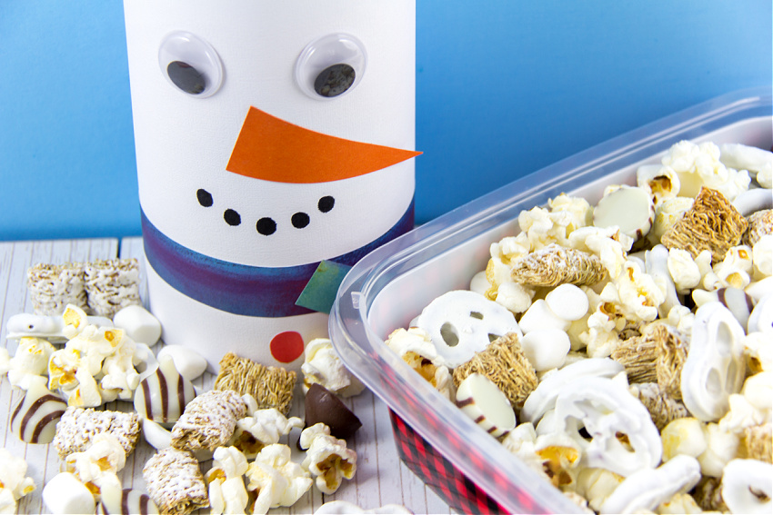 a winter snack mix for movie nights in a diy snowman container made out of an oatmeal container