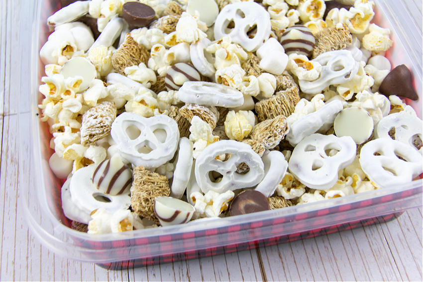 a snowman snack mix with popcorn, yogurt covered pretzels, mini marshmallows, frosted mini wheats, and hershey's s'mores