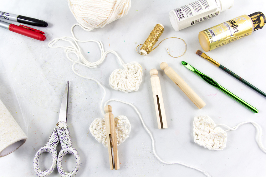 gather wood clothespins, yarn, embroidery thread, and paint to make diy angel ornaments with crocheted wings